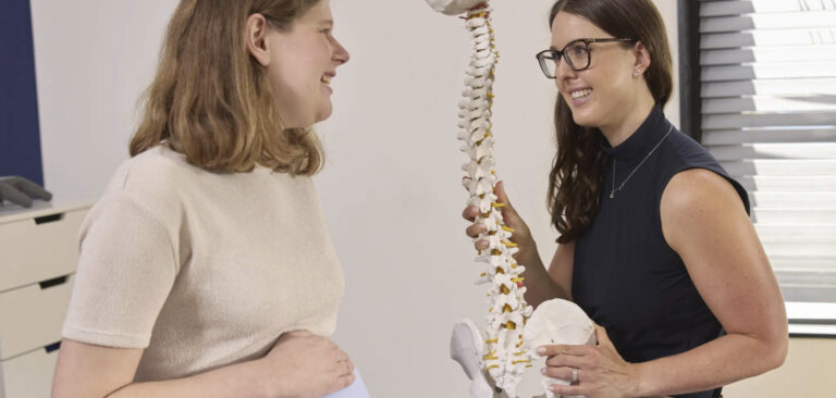Chiropractor legt vrouw die zwanger is nut van chiropractie uit