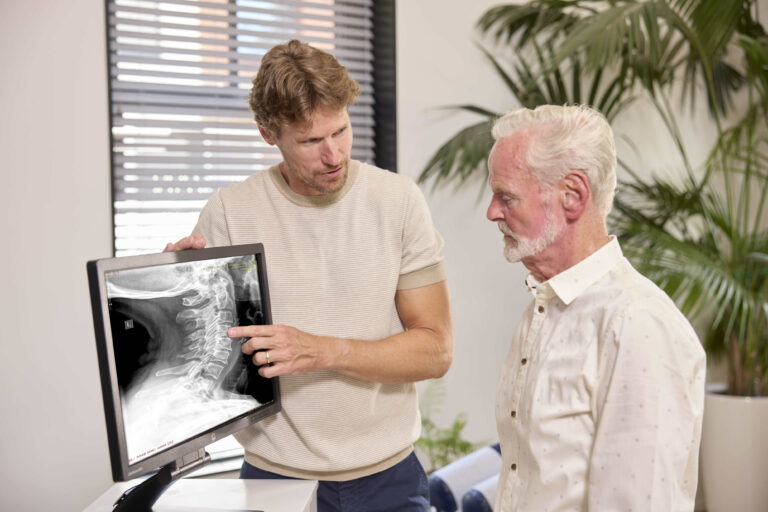 Chiropractor legt artrose behandeling uit aan cliënt