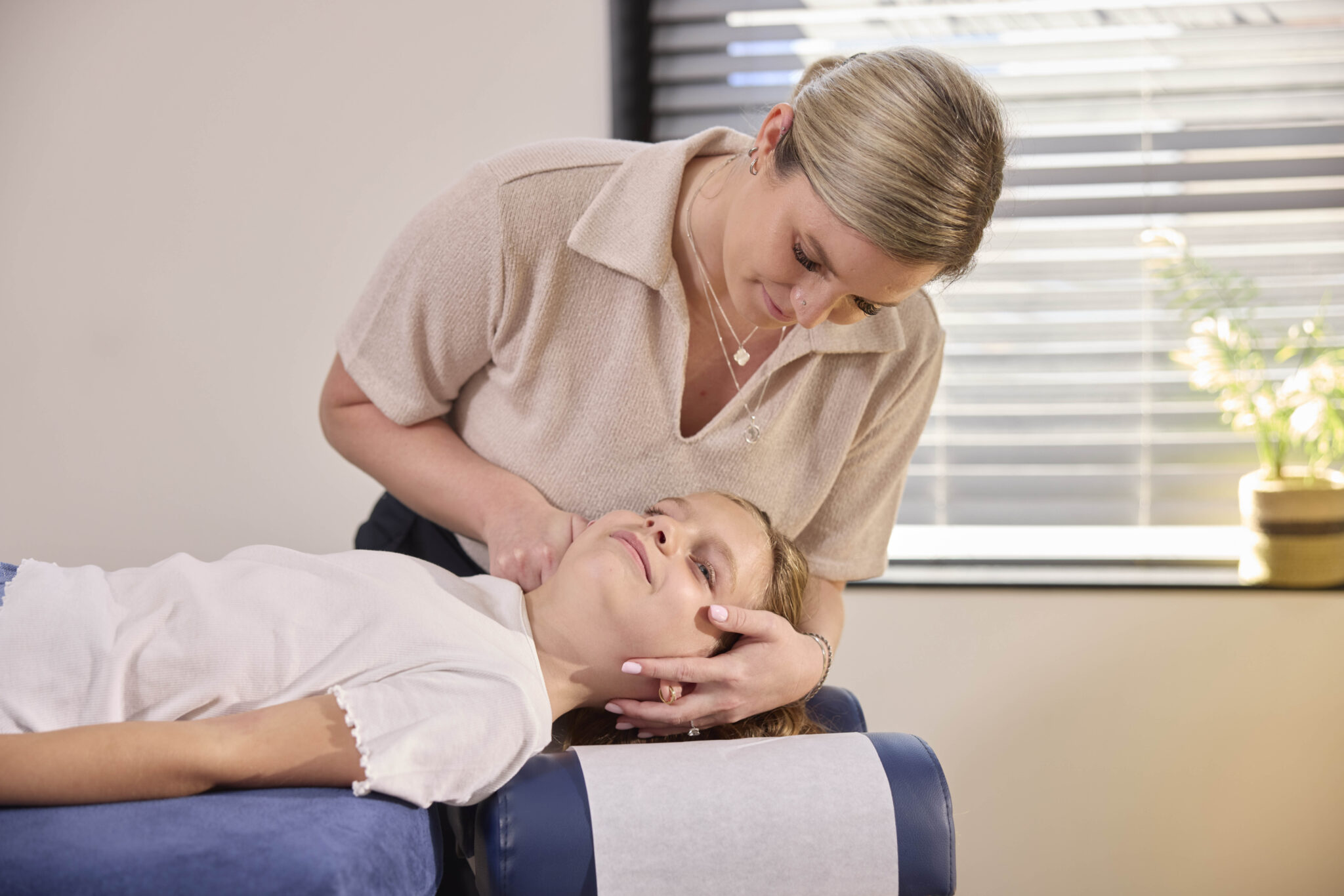 Vrouwelijke chiropractor van Huis van Chiropractie helpt kind met pijn aan nek